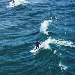 Aerial view of surfers navigating waves on a sunny day, capturing the essence of surfing.