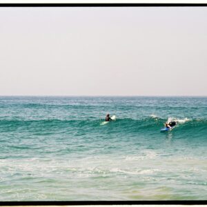 Two surfers catching waves in the vibrant blue ocean of Morocco.