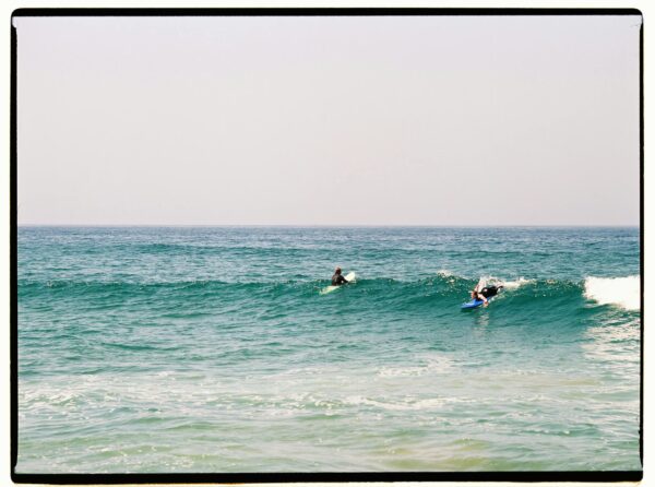 Two surfers catching waves in the vibrant blue ocean of Morocco.